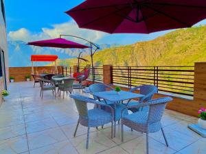 un patio con mesas, sillas y sombrillas púrpuras en Doon Nature Valley Resort, Kempty Fall Mussoorie en Mussoorie
