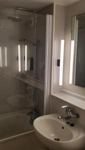 y baño con lavabo, espejo y bañera. en KYRIAD HONFLEUR - La Riviere Saint Sauveur, en Honfleur