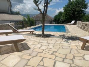 ein Pool mit Bänken und ein Baum im Hof in der Unterkunft Hotel Gjirokastra in Gjirokastër