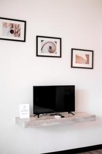 a flat screen tv on a white wall with three pictures at Casa Foresta Nan in Nan