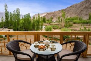 レーにあるHotel Gyalpo Residency - A Mountain View Luxury Hotel in Lehのテーブル(椅子付)、バルコニー(フルーツボウル付)