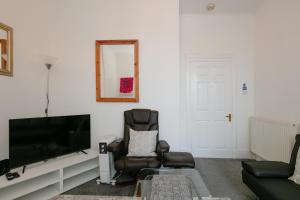 uma sala de estar com uma televisão de ecrã plano e uma cadeira em The Summit West End- Elegant Apartment with Free Parking in Prime Location em Aberdeen