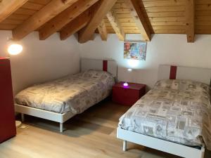 Duas camas num quarto com tectos em madeira em Passione Dolomiti em Romeno