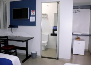 a room with a table and a bathroom with a television at PARIS HOTEL in Barreiras