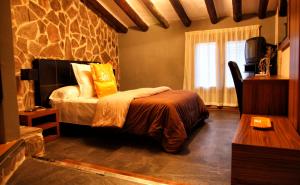 a bedroom with a bed and a stone wall at Palacete Maria Rosa in Baños de la Encina