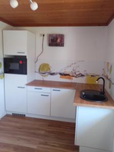 una cocina con armarios blancos y fregadero en gemütliche Ferienwohnung en Zandt