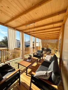 eine große Holzterrasse mit Sofas und einem Tisch in der Unterkunft Mobile House Hana E8 in Lučica