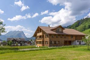 a house in a field with mountains in the background at Haus Maria-Theresia in Schoppernau