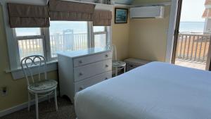 1 dormitorio con 1 cama, 2 sillas y ventanas en Capricorn Beach House, en Oak Bluffs