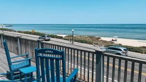 two blue chairs sitting on a balcony overlooking the beach at Capricorn Beach House in Oak Bluffs