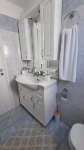 a white bathroom with a sink and a mirror at Cyclops apartment in Serifos Chora