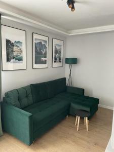 a green couch in a living room with pictures on the wall at Apartament Zeromskiego in Ostróda