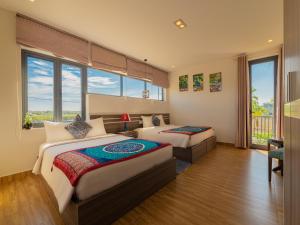 a hotel room with two beds and windows at HA Gateway Inn Hoian Pool Villa in Hoi An