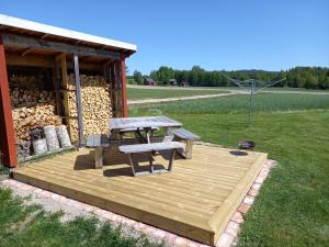 a wooden deck with a picnic table and a building at Lägenhet på landet in Torsby