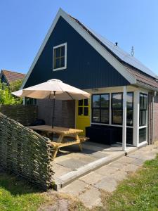 une maison bleue avec une table de pique-nique et un parasol dans l'établissement Zijper Eilant House, à Oudesluis