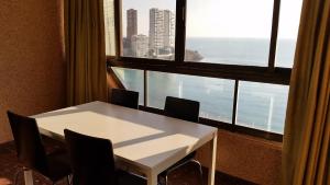 ベニドルムにあるApartamentos Don Vicenteの大きな窓のある客室で、白いテーブルと椅子が備わります。