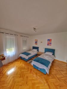 a bedroom with two beds and a wooden floor at Apartman Cvetkovic in Vranje