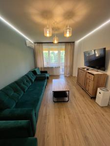 Il comprend un salon doté d'un canapé vert et d'une télévision à écran plat. dans l'établissement Brylant, à Zamość