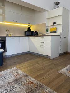 a kitchen with white cabinets and a wooden floor at Reina in Petrovac na Moru