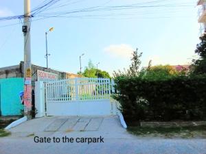a white gate to the car park with the words gate to the carpark at DCAR Residences - Transient House in Tanza