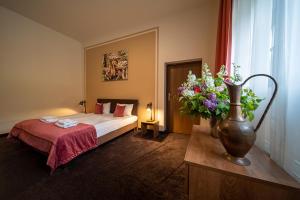 a hotel room with a bed and a vase of flowers at Folwark Książęcy in Kliczków