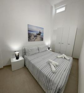a bedroom with a bed with white sheets and pillows at L'Antico Pozzo in Pozzallo