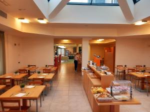 a restaurant with wooden tables and a person in the distance at Hotel Grecale - Venturina Terme in Venturina Terme