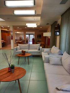 un soggiorno con divani bianchi e tavolo di Hotel Grecale - Venturina Terme a Venturina Terme