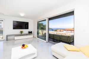 a living room with white furniture and a large window at Apartments Olea in Mali Lošinj