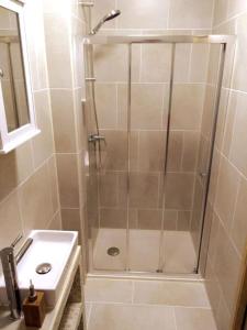 una ducha con una puerta de cristal junto a un lavabo en Spacious villa apartment with mountain view -2 bed, en Quillan
