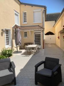 a patio with a table and chairs and a house at Gite le Mont Blanc in Le Mesnil-sur-Oger