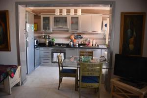 a kitchen with white cabinets and a table with chairs at Apartment in Lazordy Bay in El Alamein