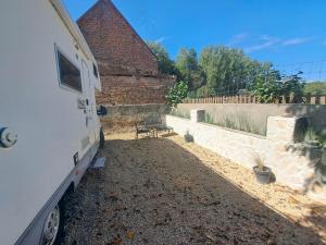 een witte trailer geparkeerd naast een stenen muur bij Camping car à 3 minutes du parc Pairi Daiza in Brugelette