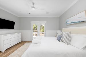 a white bedroom with a large bed and a tv at The Jungle House in Edisto Island