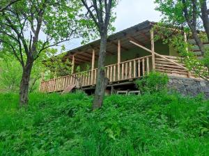 a log cabin with a deck in the woods at mesxta in Nak'alak'evi