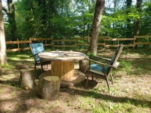 a wooden table and two chairs sitting next to a tree stump at D'En Haut tentes suspendues in Saint-Pardoux