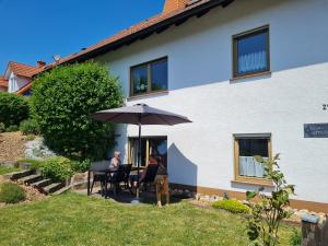 zwei Personen, die an einem Tisch unter einem Schirm sitzen in der Unterkunft Ferienwohnung Chrissi in Bischofsheim an der Rhön