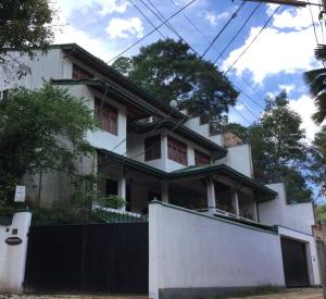 een wit huis met een hek ervoor bij Reverie Hill Bungalow, Kandy in Kandy