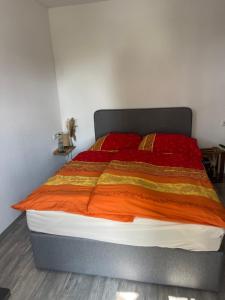 a bed with an orange and orange blanket on it at Urlaub nahe der Peene nähe der Ostsee in Rustow