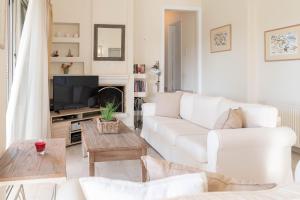 a living room with a white couch and a tv at Kos Secret Villa with private pool in (( Kermetés ))