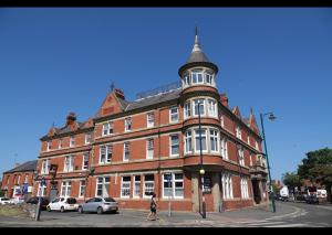 uma mulher andando em frente a um grande edifício de tijolos em Penthouse suite, Victoria Apartments em Prestatyn