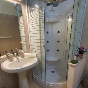 ein Bad mit einem Waschbecken und einer Glasdusche in der Unterkunft Sikelia home holiday in Siculiana