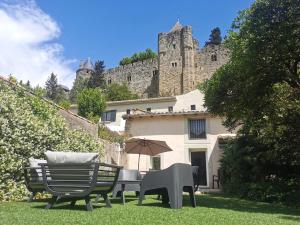 einen Garten mit zwei Stühlen, einem Sonnenschirm und einem Gebäude in der Unterkunft Le Cellier de Beaulieu, au pied de la Cité, Maison de Vacances avec Climatisation et Jacuzzi in Carcassonne