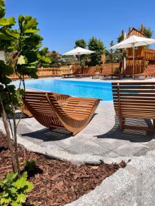 two wooden benches sitting next to a swimming pool at W Dolinie Tylicza SPA & Wellness -gabinet masażu, saunarium-plac zabaw, rowery elektryczne, animacje dla dzieci in Krynica Zdrój