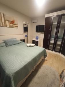 a bedroom with a green bed and a television at Centro de Gramado in Gramado
