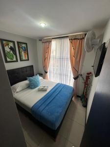 1 dormitorio con 1 cama con manta azul y ventana en Lindos y cómodos Apartamentos en Guaduales del Café, en Montenegro