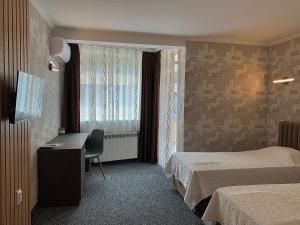 a hotel room with two beds and a desk and a window at Hotel Trayana in Stara Zagora
