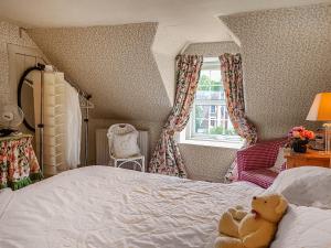 a teddy bear sitting on a bed in a bedroom at Ivy Cottage in Crieff