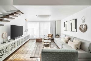 a living room with a couch and a tv at Elegant Beachfront Duplex with Private Parking in Herzliya
