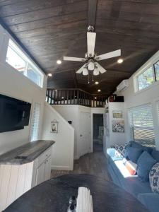 uma sala de estar com uma ventoinha de tecto e um sofá em Fox Hollow - Tiny home with Cypress Creek access, park like setting em Wimberley